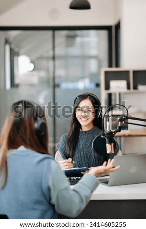 Young woman and woman wearing headphones and doing a live podcast for their channel, communication for radio podcast and technology concept
