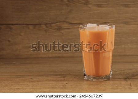 A Glass of Ice Thai Milk Tea Cha Yen on Wooden Table, Copy Space for Text 