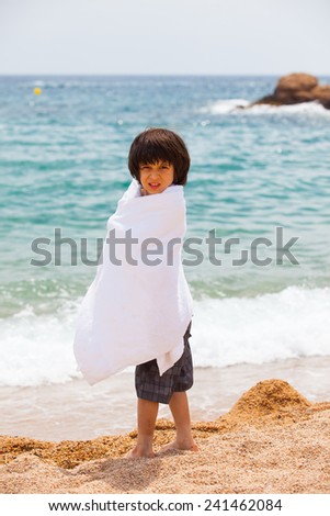 boy wrapped in a white towel on the beach