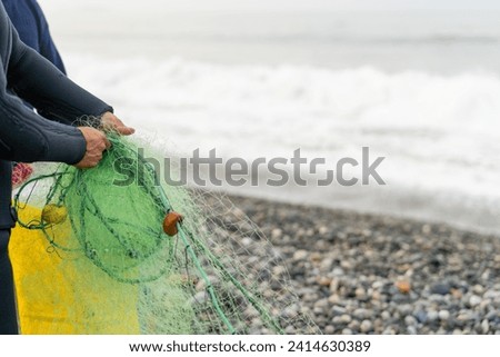 Horizontal photo with copy space of the hands of a man holding a net to fish on the beach