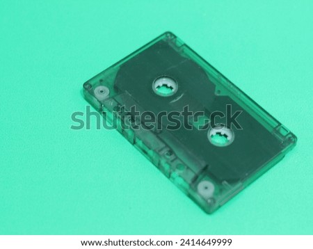 An old-fashioned cassette tape recorder on a green background