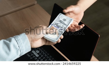Cashier giving money to businesswoman at desk in bank, closeup, Man offering batch of hundred dollar bills. Hands close up. Venality, bribe, corruption concept. Hand giving money - United States Dolla Royalty-Free Stock Photo #2414659225