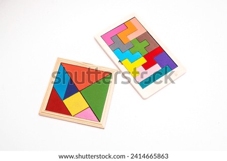 Top view of wooden tangram puzzle shapes and jigsaw puzzle on white surface