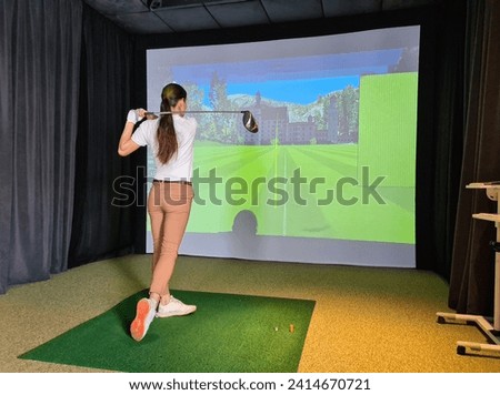 Female golfer plays golf on golf simulator. Indoor golf Royalty-Free Stock Photo #2414670721