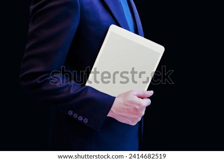 Businessman working on digital tablet against black background