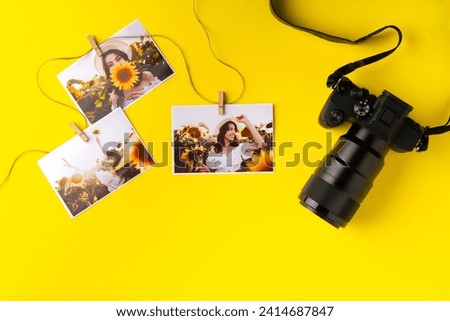 Photo camera with colorful printer photos on yellow background
