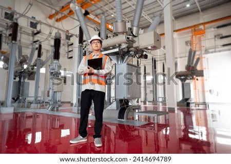 Asian engineer in safety uniform with record paper at powerhouse interior building. Royalty-Free Stock Photo #2414694789