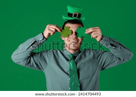 Happy young man with clovers on green background. St. Patrick's Day