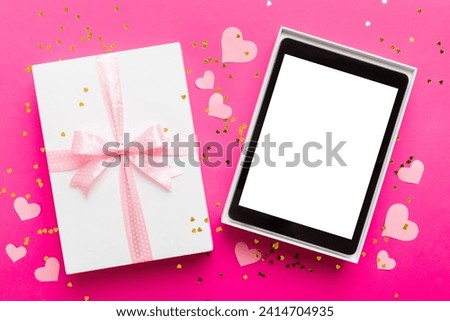 Gift box of open tablet for the holidays with a bow top view.
