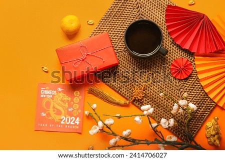 Golden dragon figure with greeting card, gift box and decor on orange background. Chinese New Year celebration