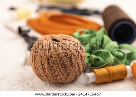 Sewing accessories: scissors, thread, thimbles, braid on gray concrete background. Side view, close up, selective focus