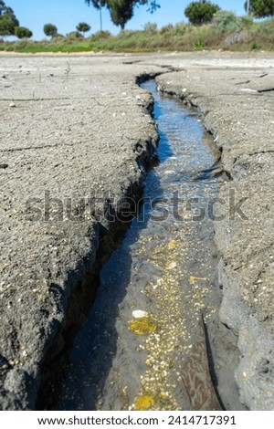 dry and cracked floor of dry river of caldera grande in the city of Barreiro with a small stream.