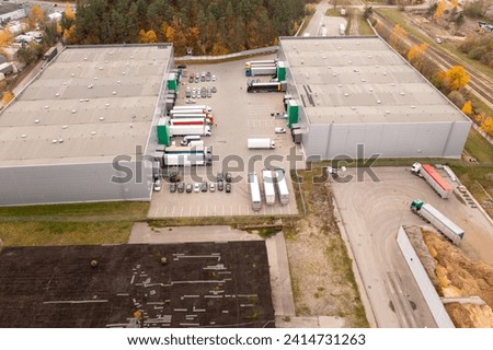 Drone photography of small logistical warehouse with parked lorry’s during autumn sunny day