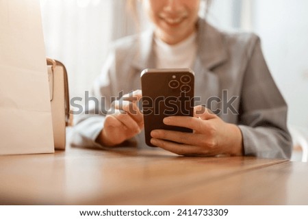 Cropped shot of a happy, attractive young Asian woman using her smartphone at a table in a cafe. chatting, scrolling on social media, shopping online. people and wireless technology concepts