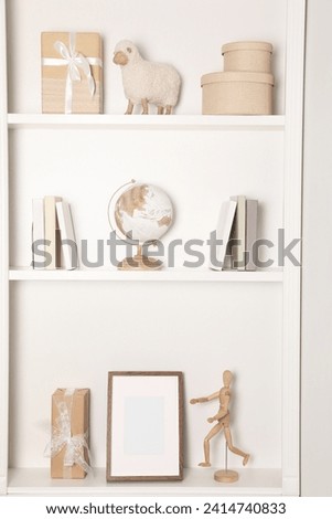White shelves with books and different decorative elements indoors. Interior design