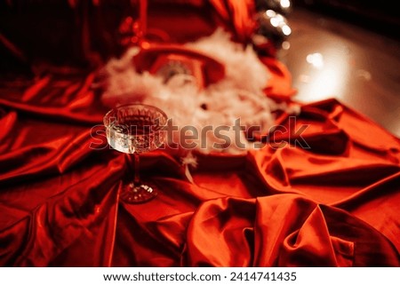 Extravagant glamour background with coupe glass of sparkly wine for love party at muffled light. Beautiful romantic burlesque place for st valentines holiday in red silk glossy sheets Royalty-Free Stock Photo #2414741435