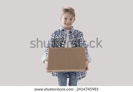 Happy strong boy holding a big cardboard box, delivery and home relocation concept Royalty-Free Stock Photo #2414745981