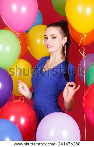 Portrait of a young attractive woman among many bright balloons