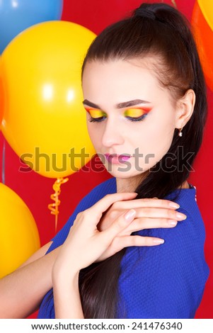 Portrait of a young attractive woman among bright balloons