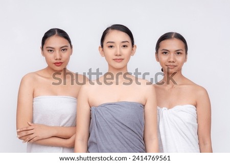 A serene portrait of three Asian women wrapped in towels, standing confidently with a subtle smile.