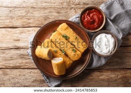 Polish Krokiety are made from rolled crepes, filled with stuffing meat, then breaded and pan-fried closeup on the plate on the wooden table. Horizontal top view from above Royalty-Free Stock Photo #2414785853