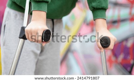  Young man with crutches with disability on the street. Selective focus and blurred background for copy. detail of hand leaning on crutches outdoors to help walk down the street Royalty-Free Stock Photo #2414791807