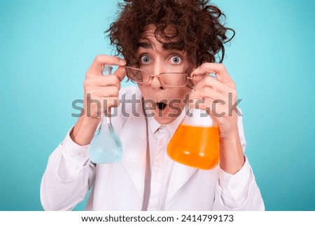 A funny doctor conducts chemical experiments with liquids. A man with test tubes. The study of the interactions of substances. Blue background.