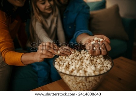 Family taking a popcorns from a bowl, focus on hands
