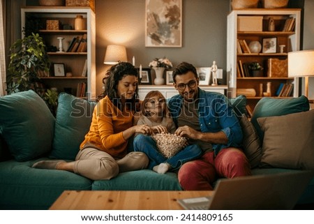 A family sitting together, watching a scary movie, and indulging in delicious popcorn in their cozy living room