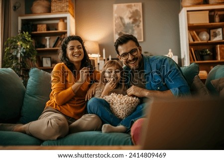 A family of three having a delightful time watching a film and snacking on popcorn