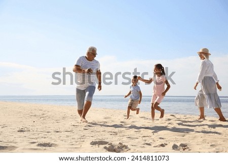 Cute little children with grandparents spending time together on sea beach Royalty-Free Stock Photo #2414811073