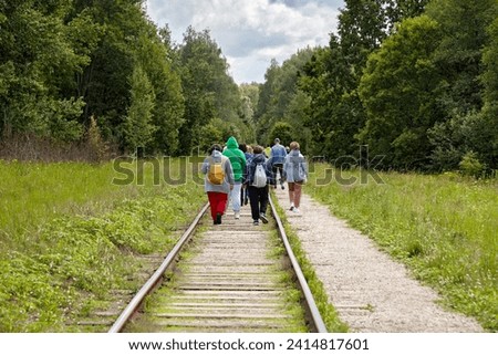 A group of migrant refugees moves along abandoned railway tracks in the forest.
