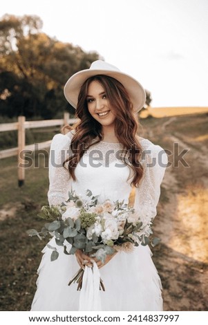 Portrait of a cute cowboy girl in a white dress with a bouquet on the background of a brown horse. Summer evening on a ranch farm at sunset