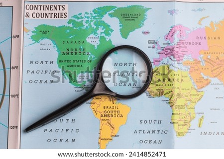 North Atlantic Ocean, magnifying glass close up with colorful world map.


