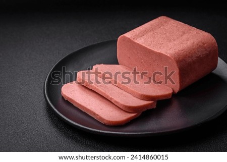 Delicious canned pink ham with salt, spices and herbs on a dark concrete background Royalty-Free Stock Photo #2414860015