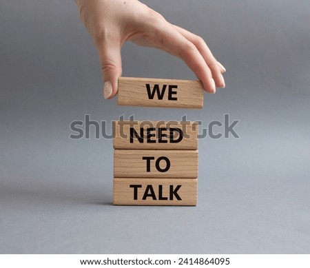 We need to talk symbol. Concept words We need to talk on wooden blocks. Beautiful grey background. Businessman hand. Business and We need to talk concept. Copy space.