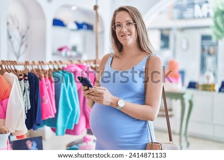 Young pregnant woman customer smiling confident using smartphone at clothing store