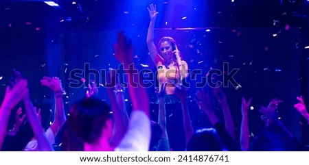 Caucasian female DJ with Turntables at nightclub. Group of diverse young people dancing in night club. Nightlife and disco dance party concept. Fun music festival Royalty-Free Stock Photo #2414876741