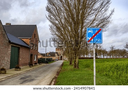 Rural road for cars with traffic sign indicating: prohibited for tractors, bicycles, horses, scooters and pedestrians, Alden Biesen castle in background, cloudy day in Bilzen, Limburg, Belgium