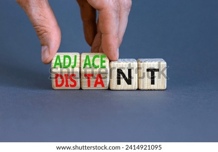 Adjacent or distant symbol. Businessman turns beautiful wooden cubes and changes word Distant to Adjacent. Beautiful grey table grey background. Copy space. Business adjacent or distant concept.