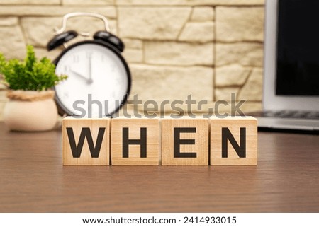 WHEN on wooden cubes amid a clock, laptop, and plant signifies timely decision-making. It visually highlights the intersection of time, technology, and productivity.