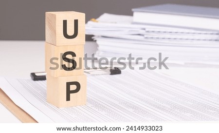 USP - Unique Selling Proposition on wooden blocks against a backdrop of business papers conveys a finance concept emphasizing individuality and market distinction