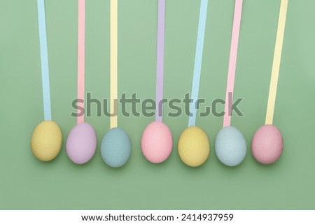 Row of different colored eggs with fun leading geometric lines on green background. Copy space simple pastel rustic background for traditional Easter holiday card