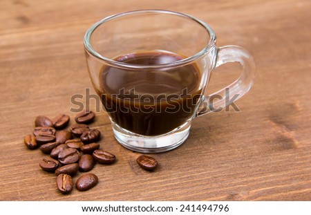 Cup of coffee and coffee beans on wooden table close up view