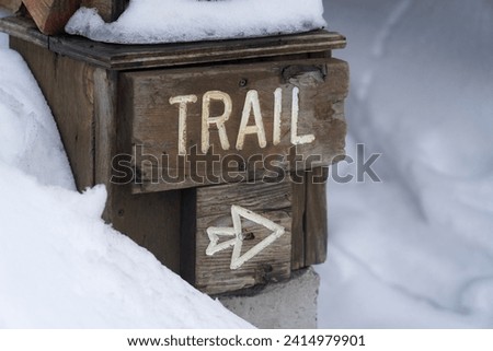 Trail sign with arrow surrounded by snow.  