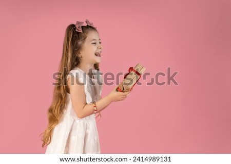 The little girl with a very, very beautiful smile who is happy to have received a present for her birthday. She is fascinated by the small gift and is very enthusiastic about what is in it. Picture on