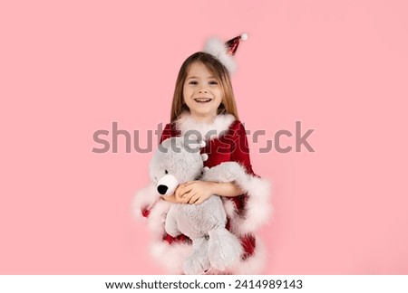 Christmas, teddy bear and happiness with a girl in studio with pink background, dressed in red Christmas dress. Bears the most wonderful Christmas gift for children, joy and holiday.