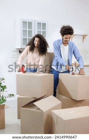 African American couple, man and woman, collect clothes and personal belongings in cardboard boxes for moving. happy young people relocating to new home. purchase of residence, mortgage or rental.  Royalty-Free Stock Photo #2414990647