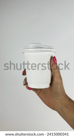 white paper cup with place for logo in female hands with pink manicure