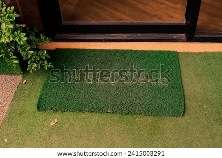Welcome door mat with word Welcome near entrance door,green Door mat for the entrance to a cafe, restaurant and shop.